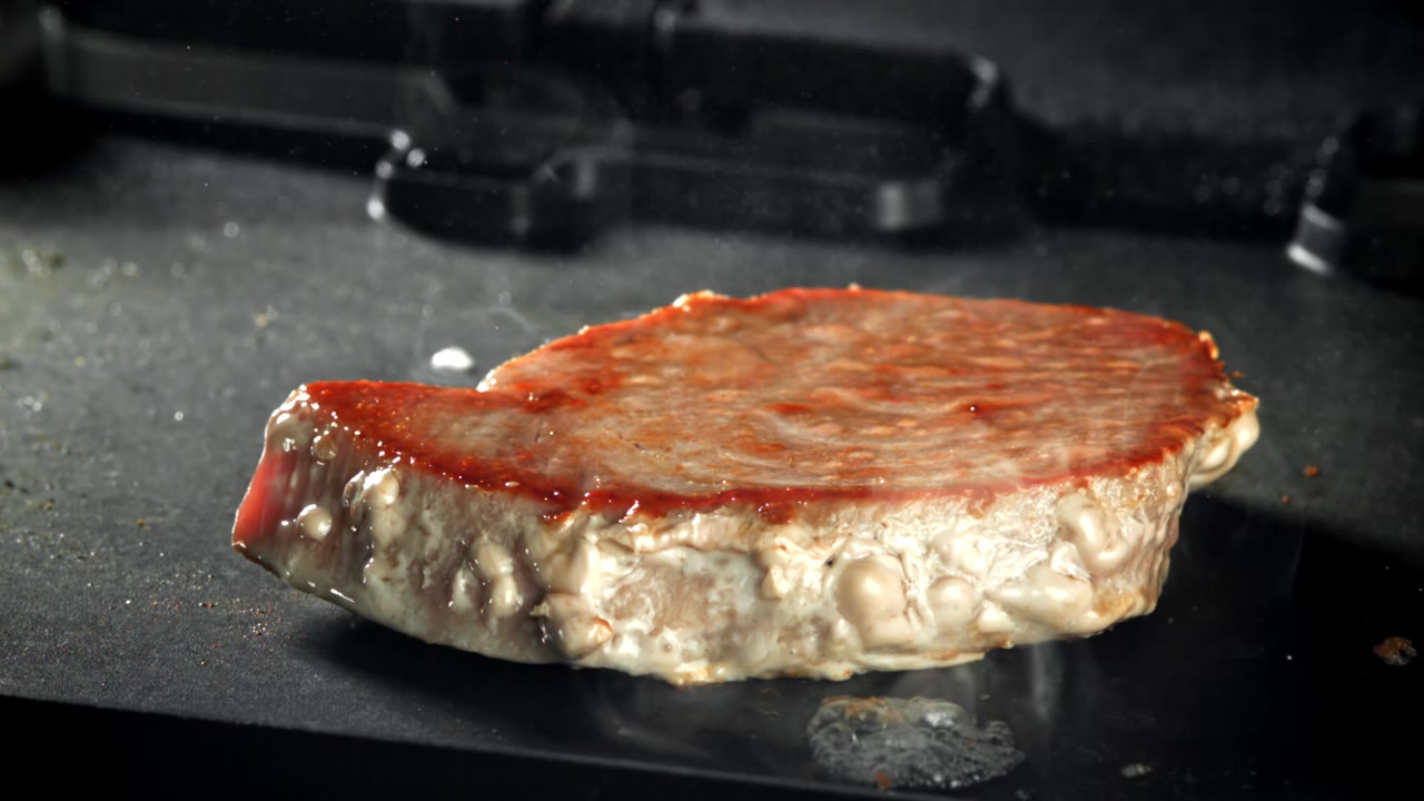 Primo piano di una bistecca che sfrigola su una piastra calda
