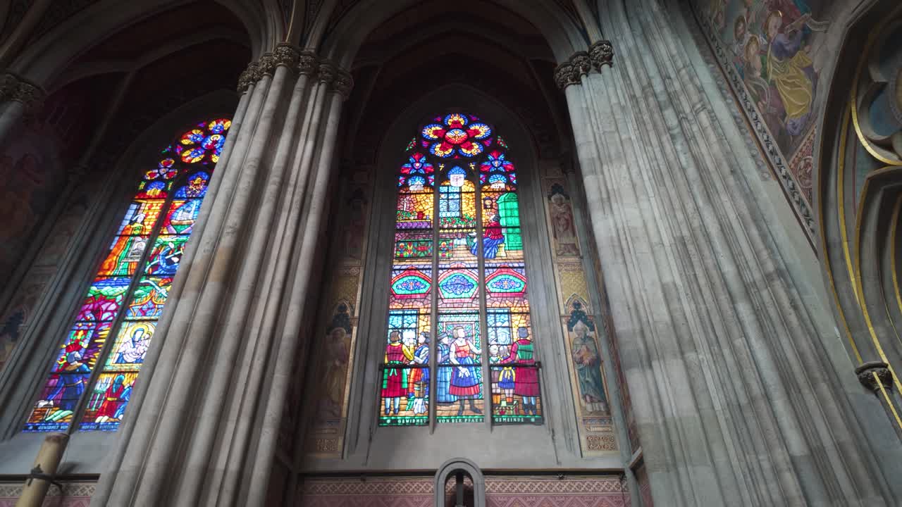 Detailed view of an altar with vibrant stained glass windows inside Votive Church, Vienna, Austria