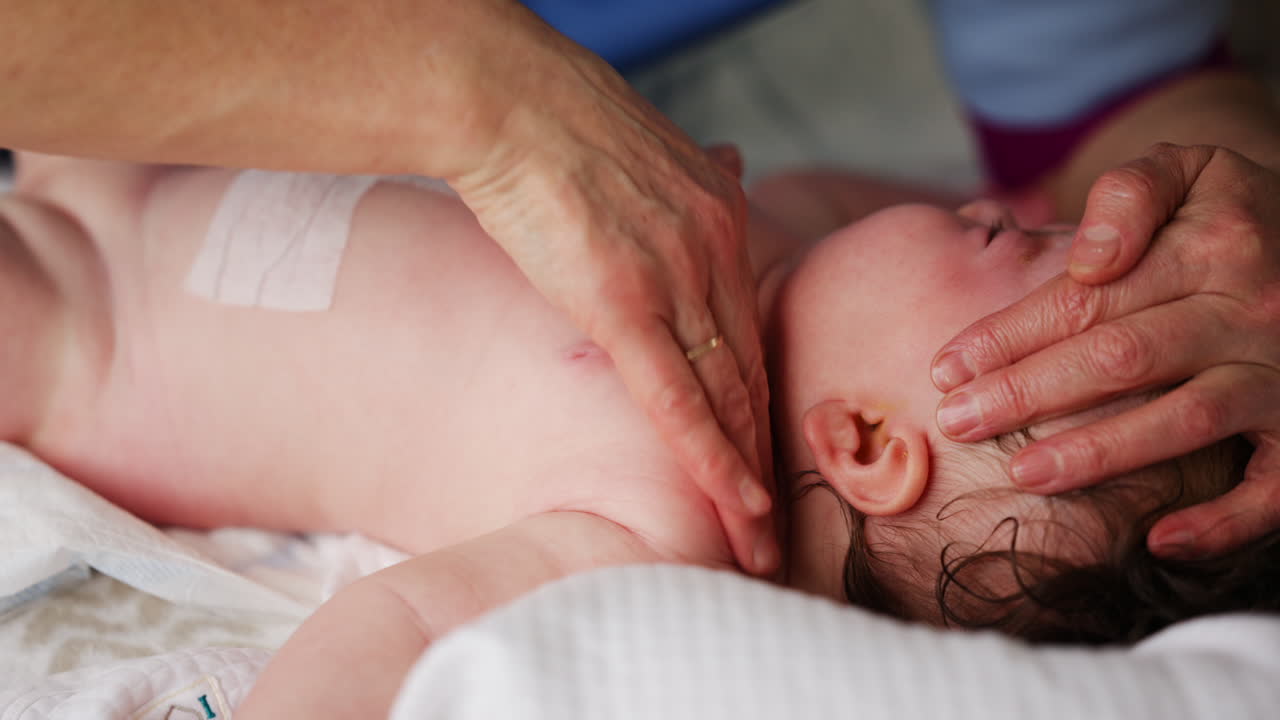 Bambino sdraiato sulla schiena mentre un adulto lo massaggia ed esegue esercizi di mobilità.