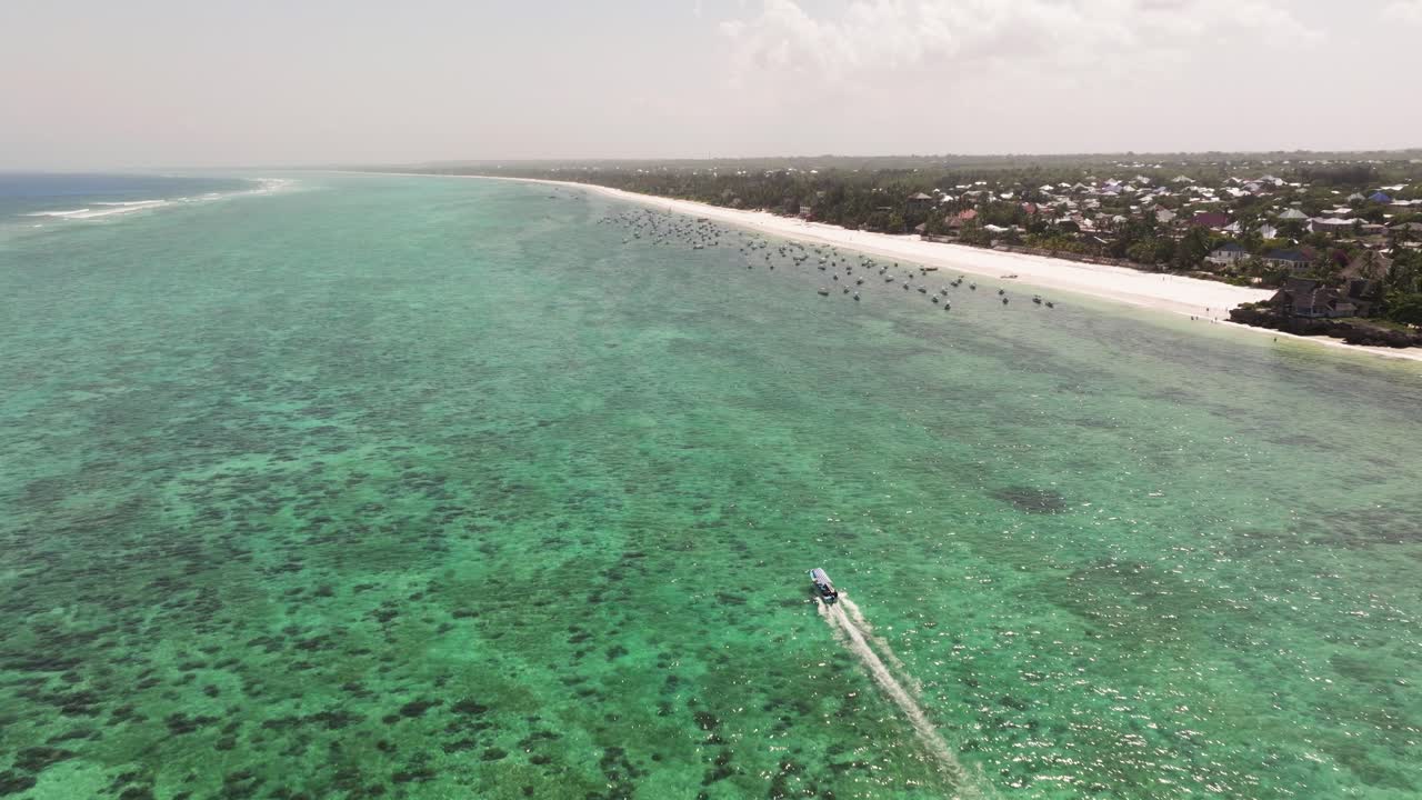 Matemwe beach, Drone tracking over boat racing in shallow water near white sand beach in Zanzibar with visible reef lines below