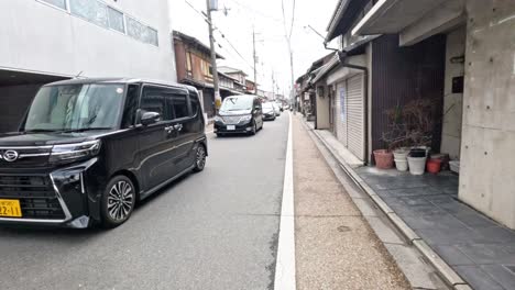 cars driving down a narrow traditional street