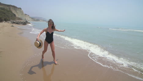 una mujer en traje de baño salta al océano en la playa.