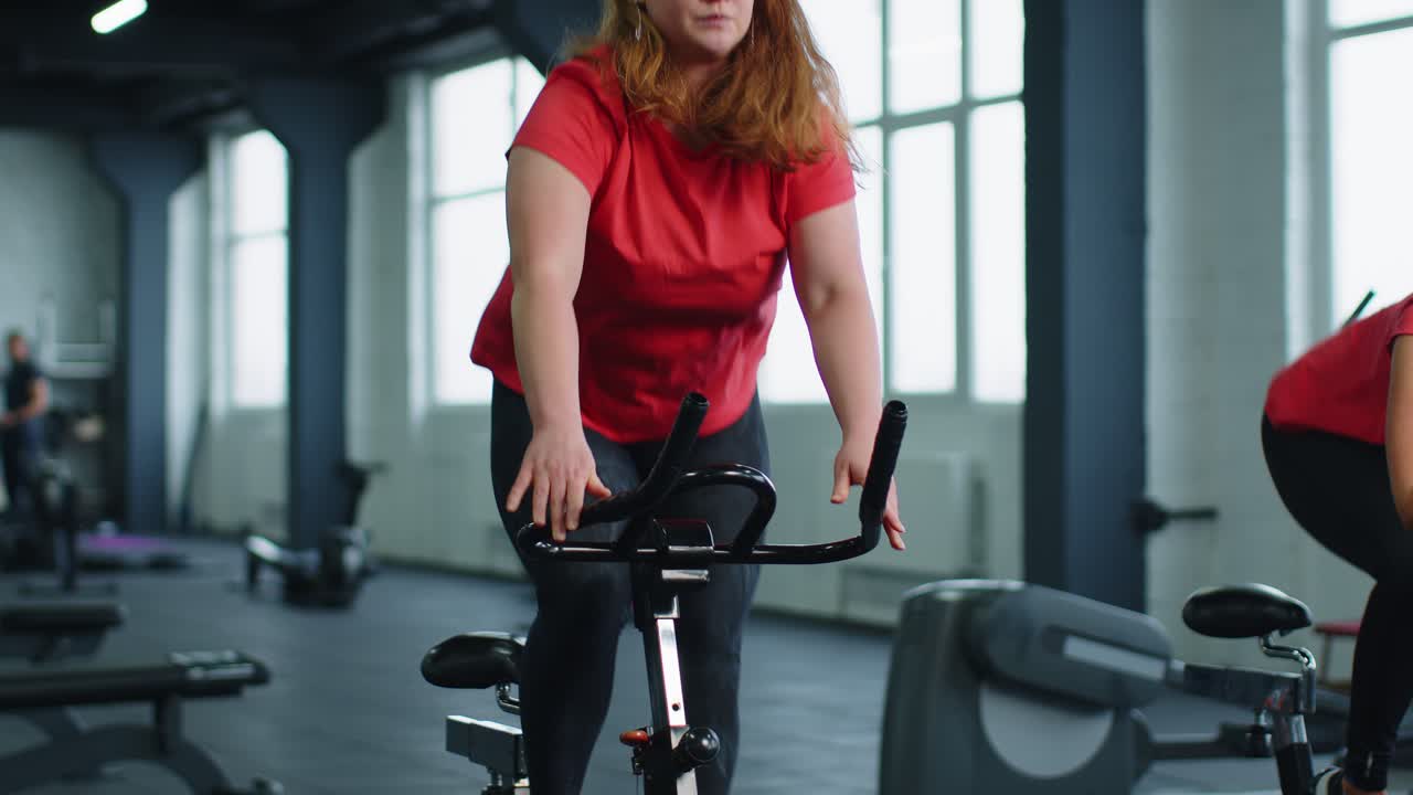 Group of smiling friends women class exercising training spinning on stationary bike at modern gym
