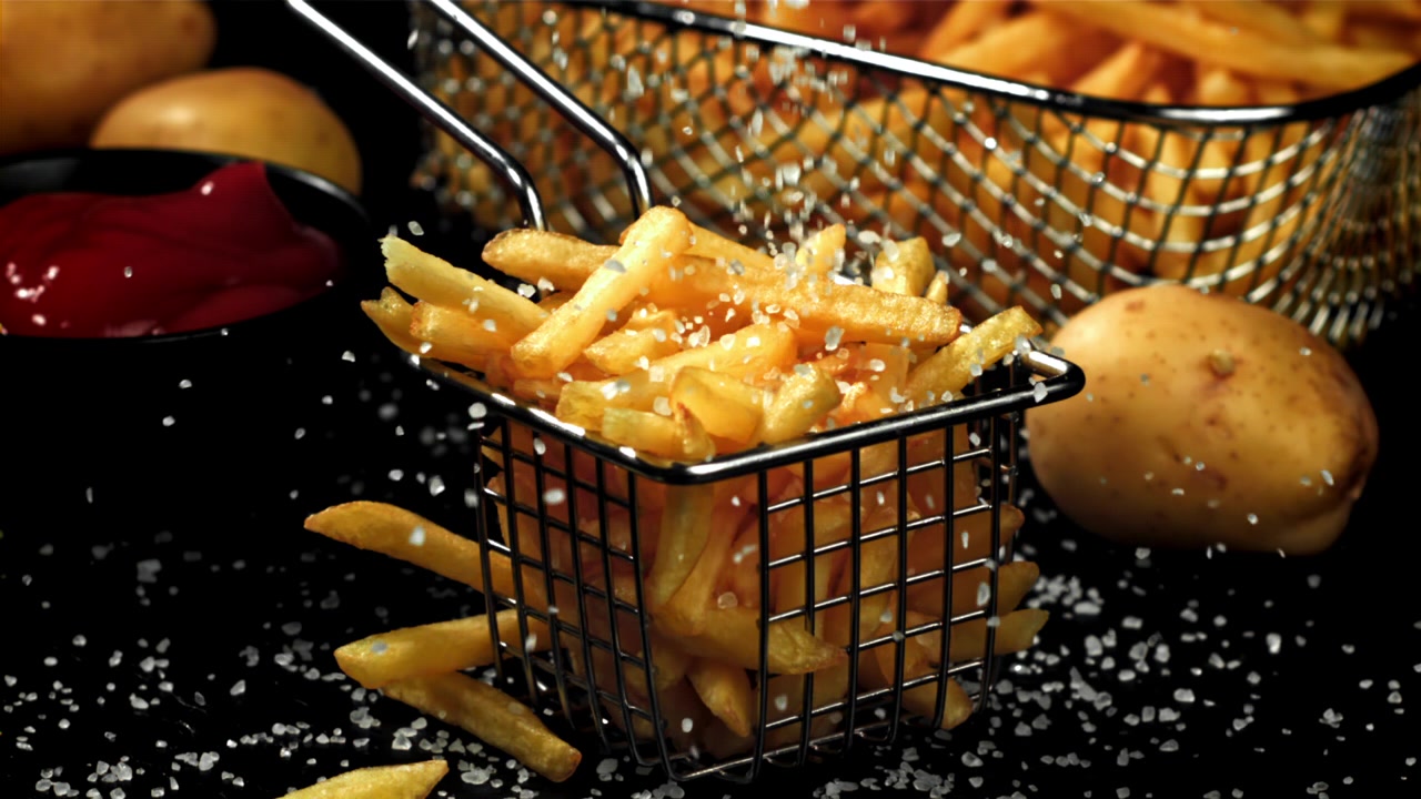 Sal Sendo Polvilhado em Batatas Fritas Douradas em uma Mini Cesta de Fritura
