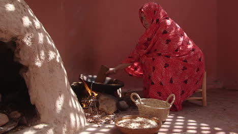 moroccan woman by fire in hut preparing dinner