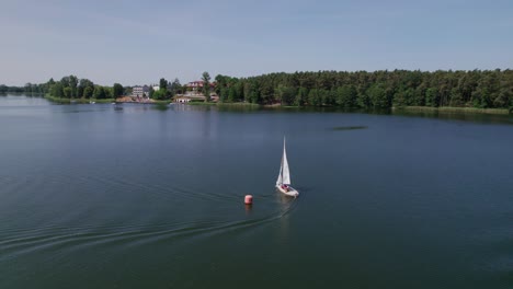 Sailboat-sail-on-a-lake-in-the-forest,-drone-parallax-shot