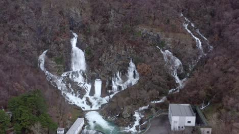 aerial - multiple waterfalls coming out of rocky hillside joining streams, fly in