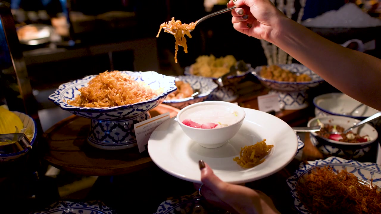 Close-up of a Hand Serving Thai Sweet Pickled Turnip at a Buffet