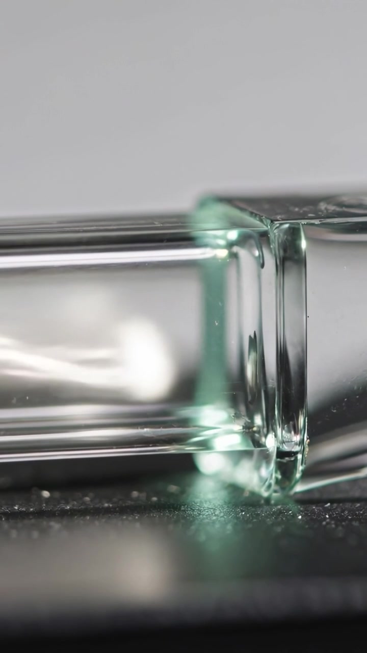 Vertical video: Reacting to light shift, clear tube accepting bead on dark table