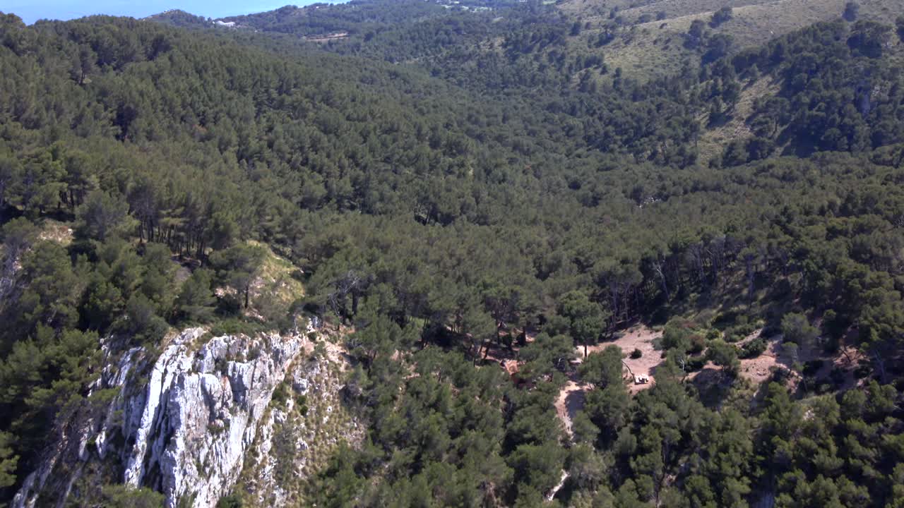 Experience the stunning landscapes of Coll Baix, nestled near Puerto de Alcudia in Mallorca. Enjoy the view of lush pine forests and the sparkling sea in the distance.