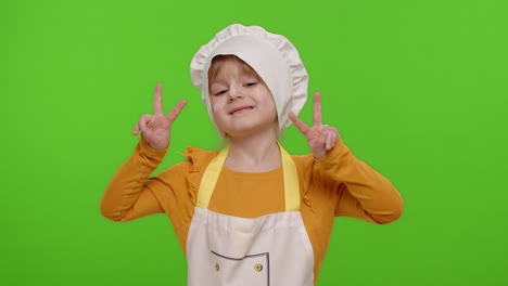 little child girl dressed like chef cook showing victory sign, hoping for success and win, peace