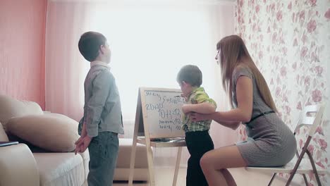 Mother teaches little son to write the figures