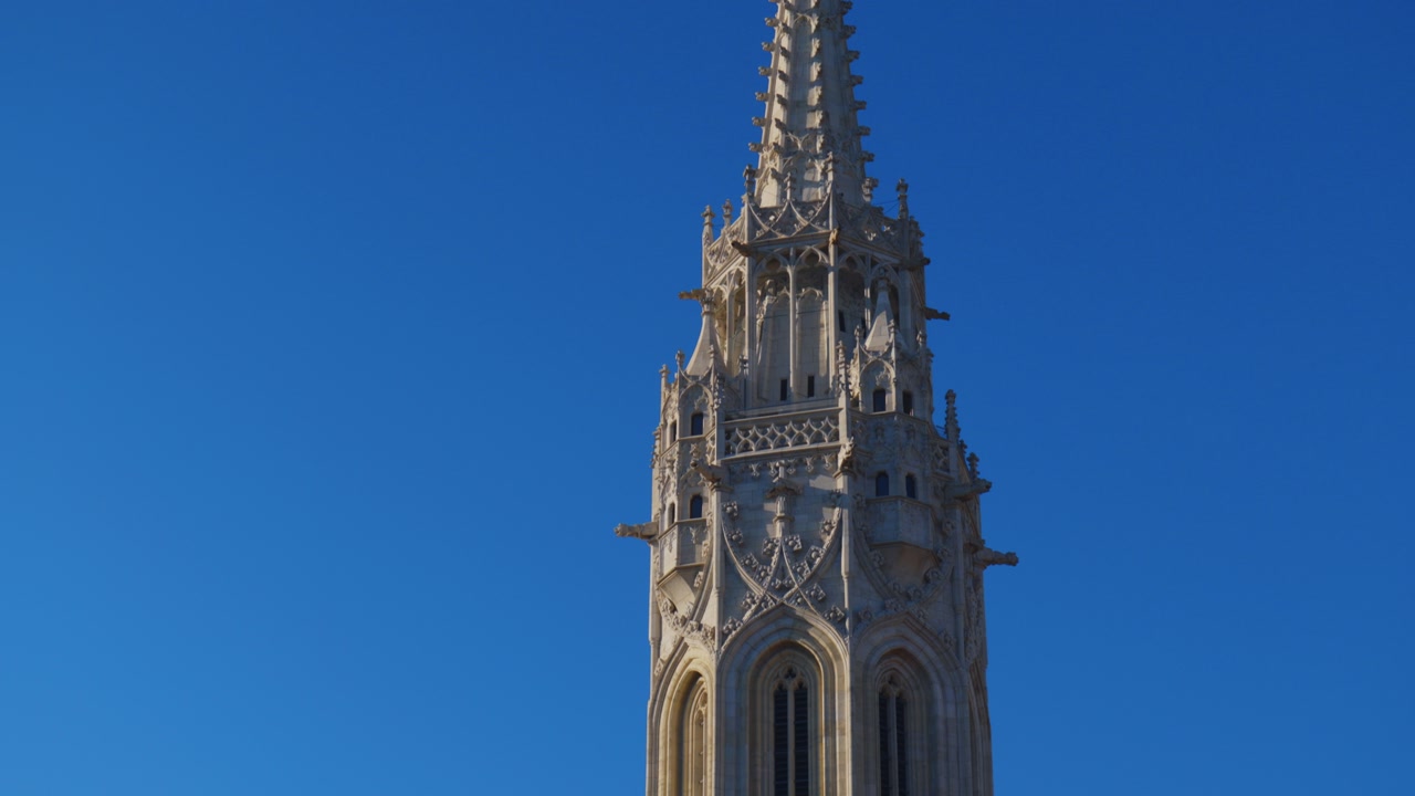 Tilt up shot of Matthias Church in Budapest showcasing gothic tower and colorful roof