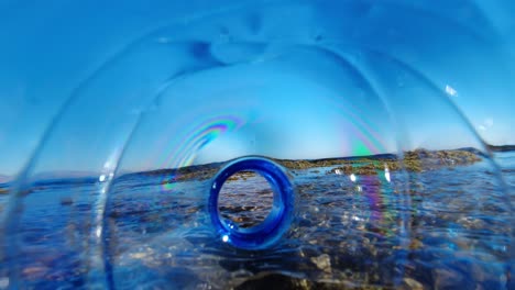botella de plástico que contamina el océano a medida que se desplaza en las olas de marea, como se ve desde el interior de la botella