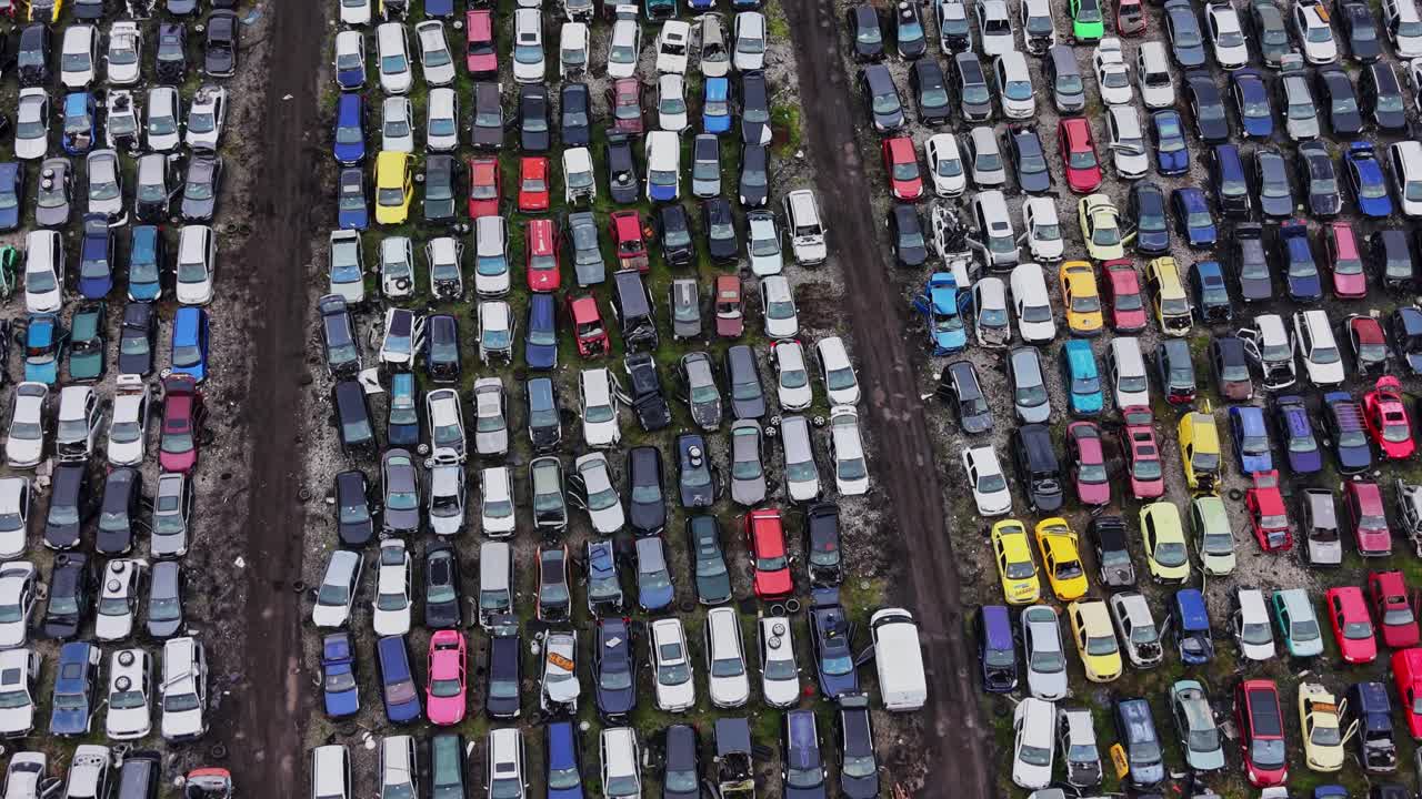 Mange biler parkeret på en stor losseplads i dagslys