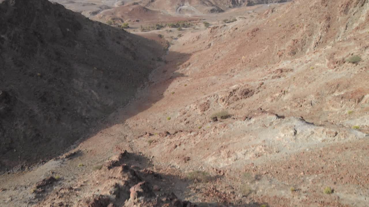 아랍 에미레이트 하타의 바위산 꼭대기에 서 있는 젊은 남성의 무인 항공기에서 공중 촬영을 공개