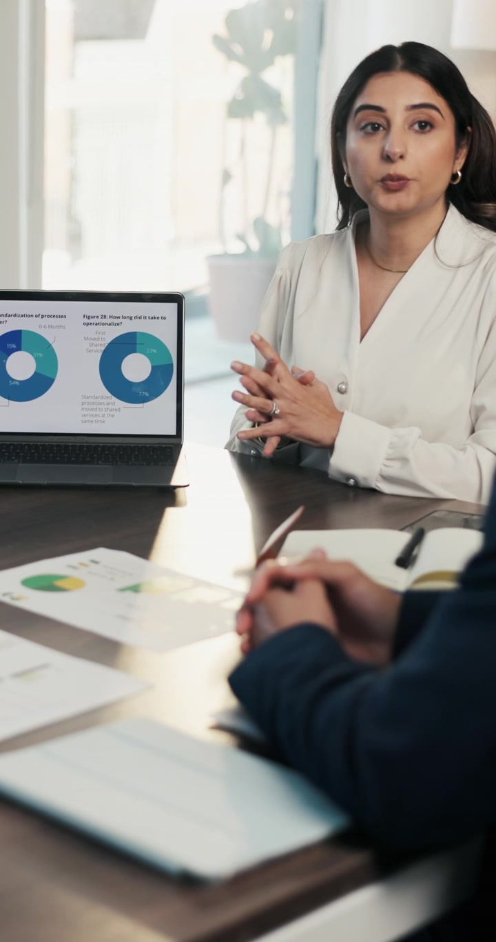 Imprenditrice che presenta grafici di dati a un collega durante una riunione in ufficio