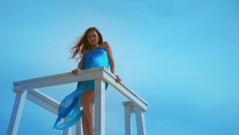 redhead woman on watchtower on sky background. bottom view of young woman