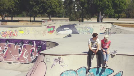 young couple sitting on a wall at a skate park