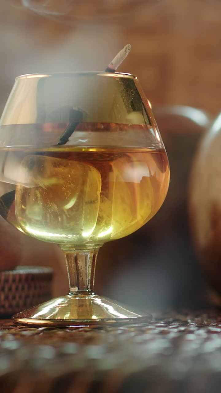 Slow motion rotating golden drink with smoke rising, evoking gentlemen club and lounge ambience