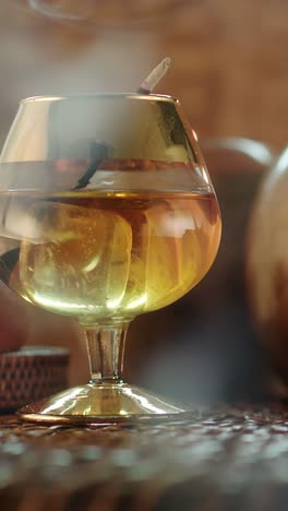 slow motion rotating golden drink with smoke rising, evoking gentlemen club and lounge ambience