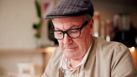 senior man adjusting glasses in a cafe