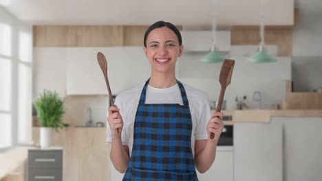 Glückliche-Indische-Hausfrau-Posiert-Mit-Löffel-Und-Spachtel