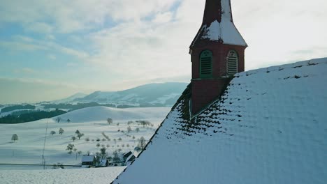 Imágenes-De-Drones-Sobrevolando-Una-Pequeña-Capilla-Y-Un-Idílico-Paisaje-Invernal-En-La-Suiza-Rural