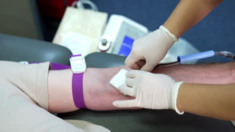 tourniquet is attached to the forearm of a donor. gloved hands of a nurse insert a catheter needle into the vein of a person. close up.