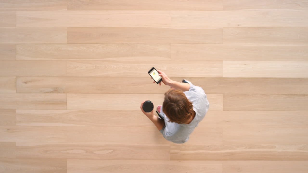 mujer usando hoverboard, teléfono inteligente y taza de café en un interior