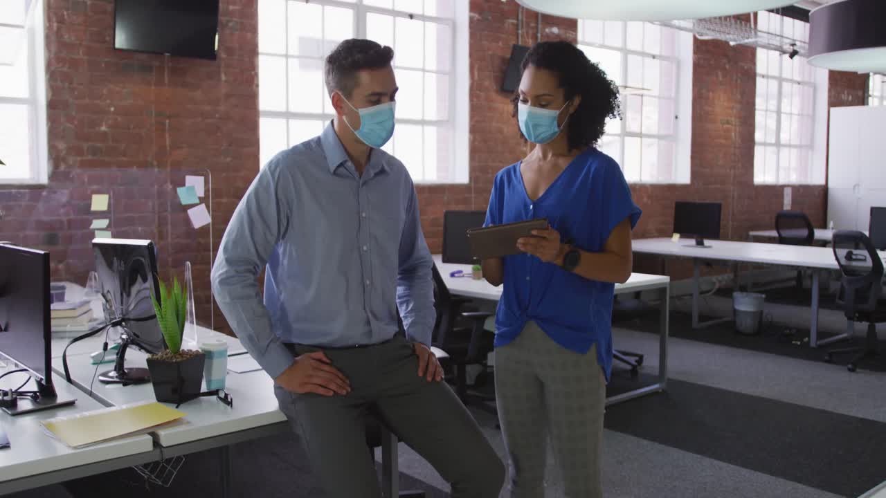 Diverse race male and female businessmen walking discussing through corridor wearing facemask