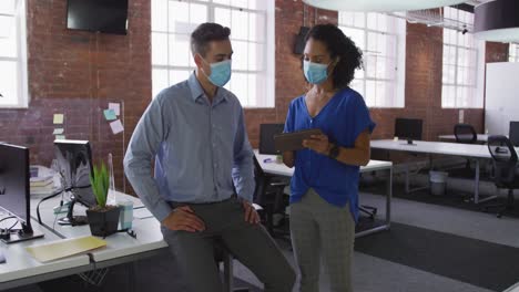 diverse race male and female businessmen walking discussing through corridor wearing facemask