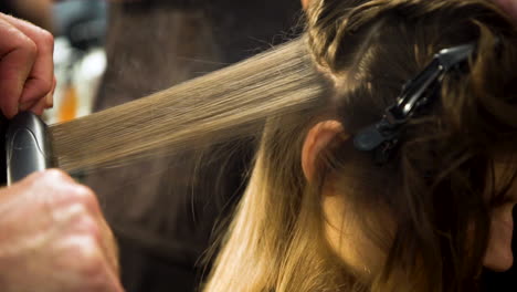 estilista alisando el cabello de la modelo con una plancha en el backstage de un desfile de moda