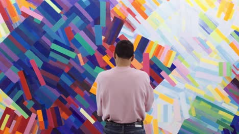 man looking at the colorful painting on the wall -wide