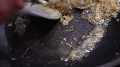 minced garlic with sliced onion being mixed in hot black pan with heated oil