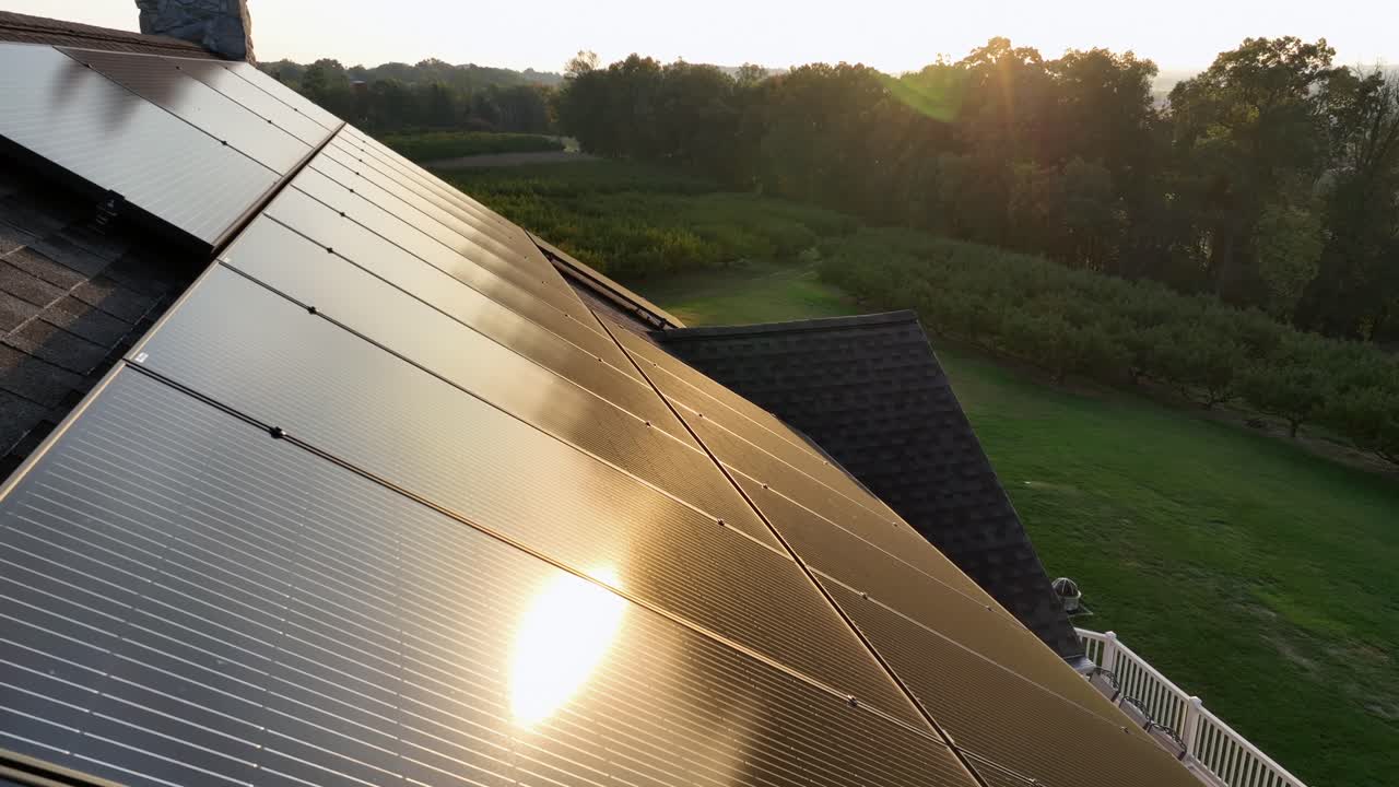 Solar panels on roof of american house during golden sunset. green grass in garden. Quiet suburbia. Production of green energy. Aerial tilt up wide shot. Mississippi, USA