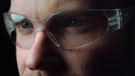 close up of face of focused man opening beautiful blue eyes with glasses.