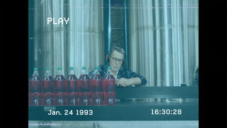 wearing headphones, man observing bottles in industrial setting, focusing on details