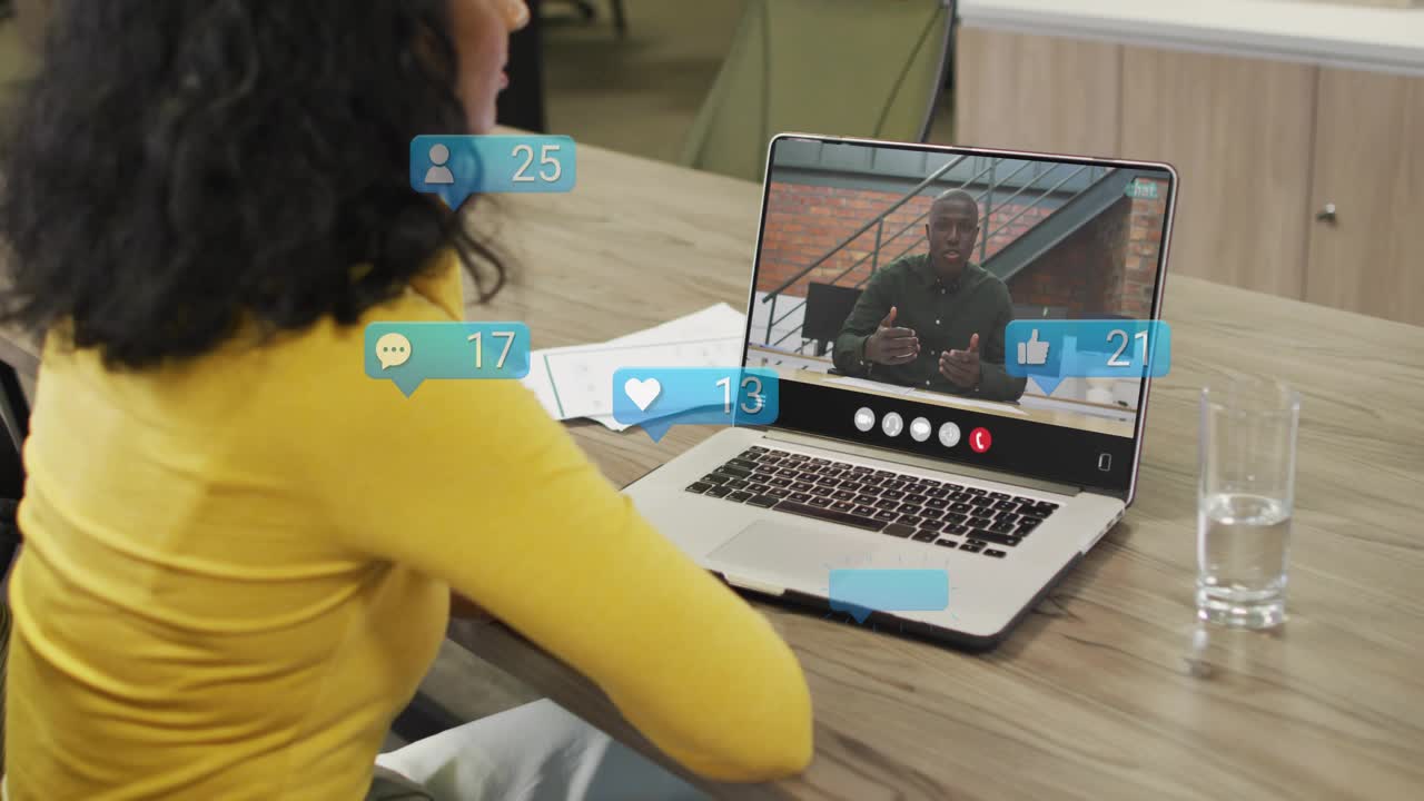 Donna che apre il laptop in una videochiamata di lavoro, mentre le icone social salgono sullo schermo mostrando il coinvolgimento.