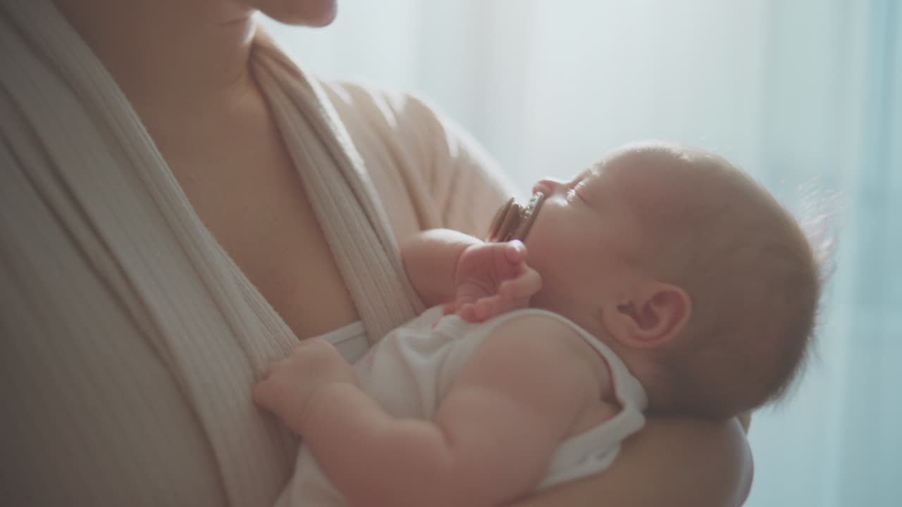 Mother holding sleeping baby in baby carrier