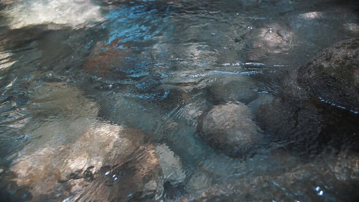 Ripresa ravvicinata al rallentatore di rocce sotto acqua cristallina di un fiume