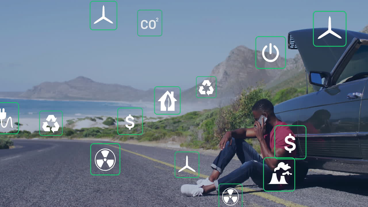 Sitting by car on coastal road, man viewing animation with digital icons