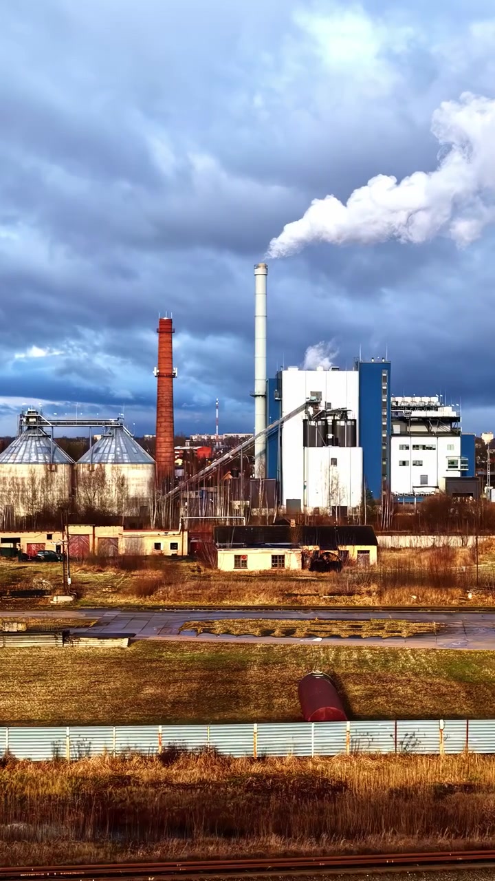 Complesso industriale che rilascia fumo bianco dalla sua ciminiera in un cielo nuvoloso