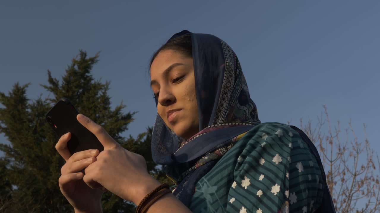 Young Muslim Female Teenager Using Mobile Phone During Sunset