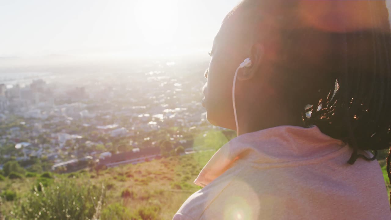 아프리카계 미국인 여성 이 야외 에서 운동 을 하고 해 가 지는 시골 에서 이어폰 을 착용 하고 있다