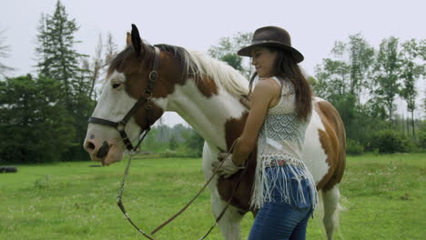 zelfverzekerde jonge cowgirl hechting met haar volwassen mannelijke pinto paard