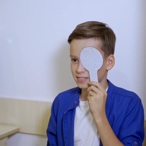 test vision in eye clinic. small boy is holding ophthalmology plate. pediatric concept