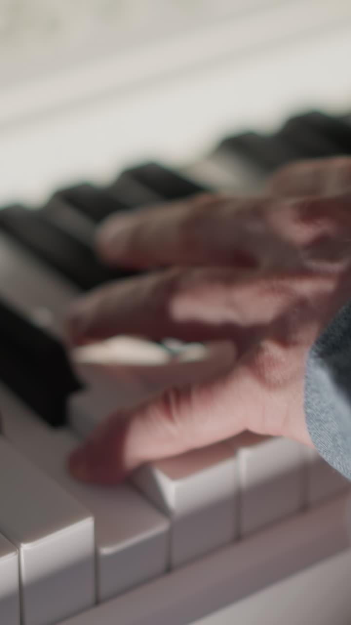 toma de primer plano de manos con mangas largas azules tocando un piano blanco. centrarse en los dedos y las teclas captura el movimiento y la habilidad involucrada en la interpretación de la música, con el fondo suavemente borroso
