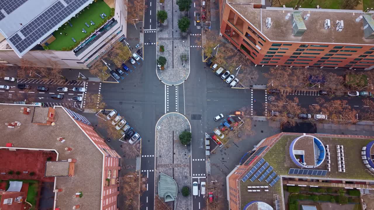 Modern street intersection with cars and trees in the Poblenou district of Barcelona, Spain. Aerial drone top-down view