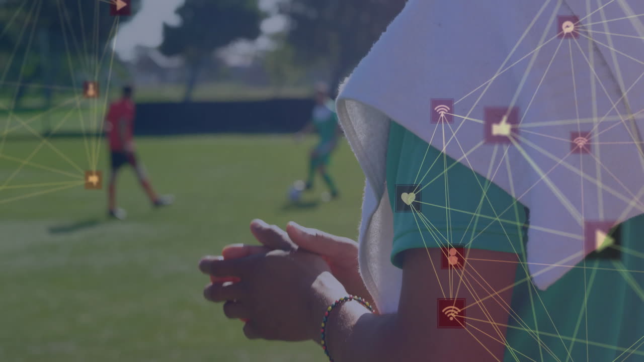 Coach clapping while players dribbling soccer ball on field, social media marketing icons glowing